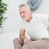 Elderly man holding his lower back in pain.