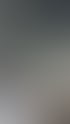 Eine Kamera auf einem Stativ filmt eine Frau im weißen Laborkittel, die an einem Schreibtisch sitzt, während sie auf dem Kamerabildschirm zu sehen ist.