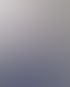 Eine Frau mit braunen Locken und Brille lächelt und trägt ein blau-weiß gestreiftes Langarmshirt vor verschwommenem Hintergrund.