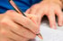 Hand mit Stift schreibt einen Nachtrag auf Papier
