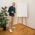 Ein lächelnder Mann in grünem Hemd und beiger Hose steht neben einem leeren Flipchart.