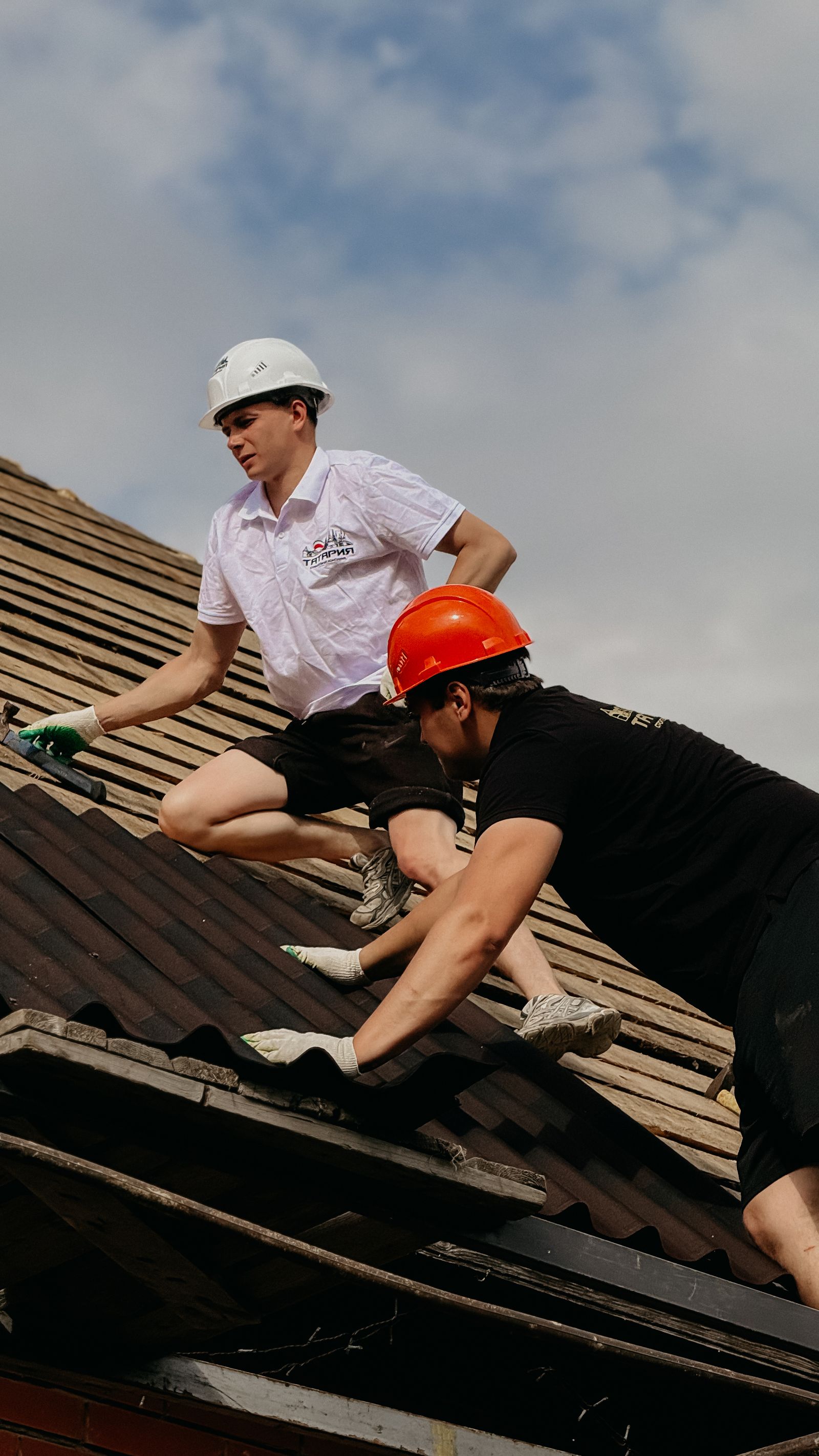 Two roofers working together along a residential roof slope