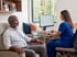 A medical professional in blue scrubs monitors a man wearing an EEG cap during a neurological brain scan.