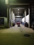 Ein roter Sportwagen steht nachts zur Wartung auf einer Hebebühne in einer hell erleuchteten Kfz-Werkstatt.