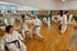 Karate-Gruppe beim Training mit Partnerübungen in einer Trainingshalle mit Spiegelwand in Leipzig