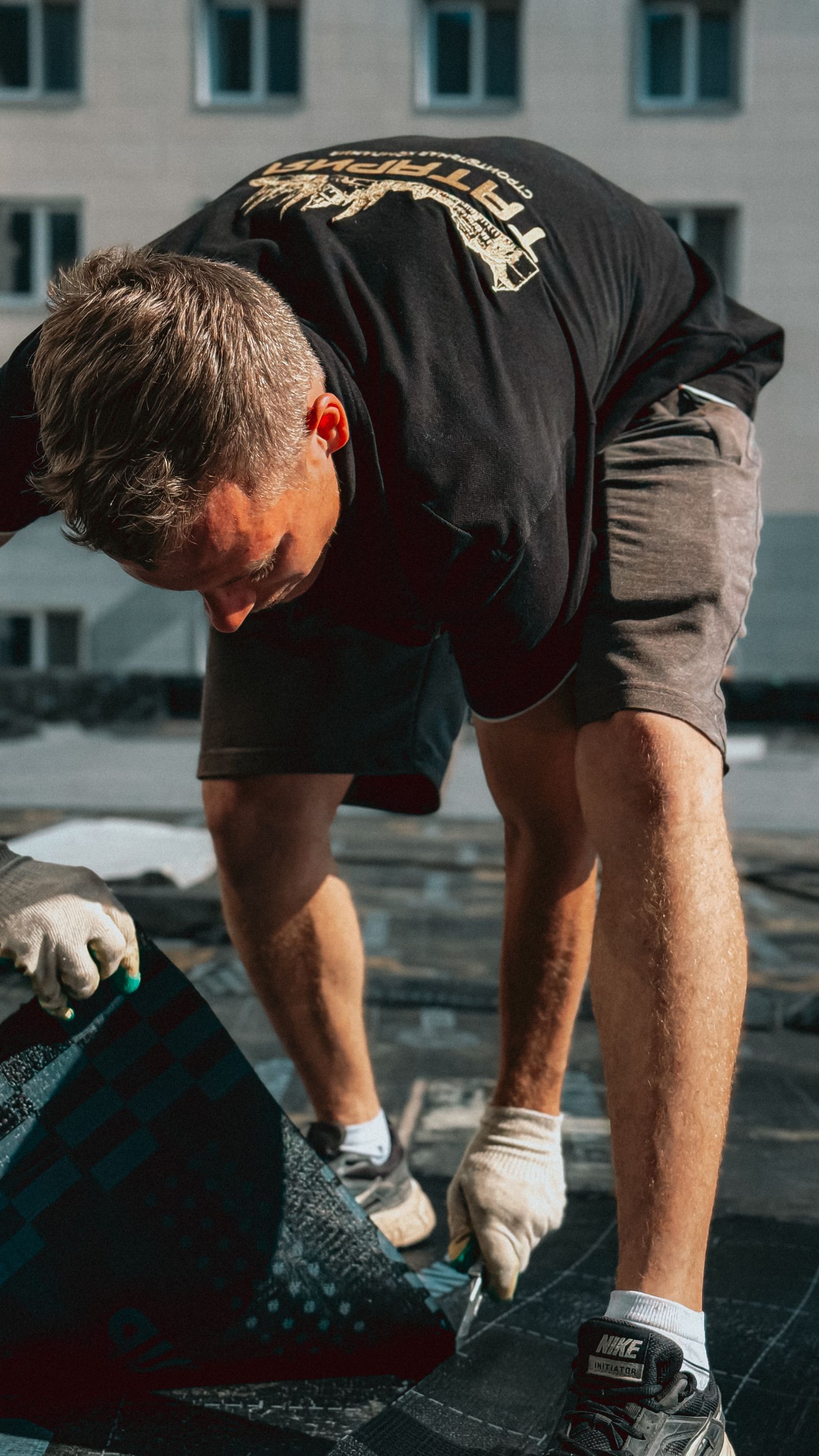 Roofer laying asphalt shingles on a residential roof slope