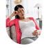 A pregnant woman in a pink cardigan sits on a couch holding her belly and head with a pained expression.