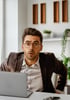 Mann mit Brille am Laptop, der mit offenem Mund und weiten Augen überrascht schaut.