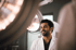 A smiling male doctor in a white lab coat stands in a hospital operating room under surgical lights.