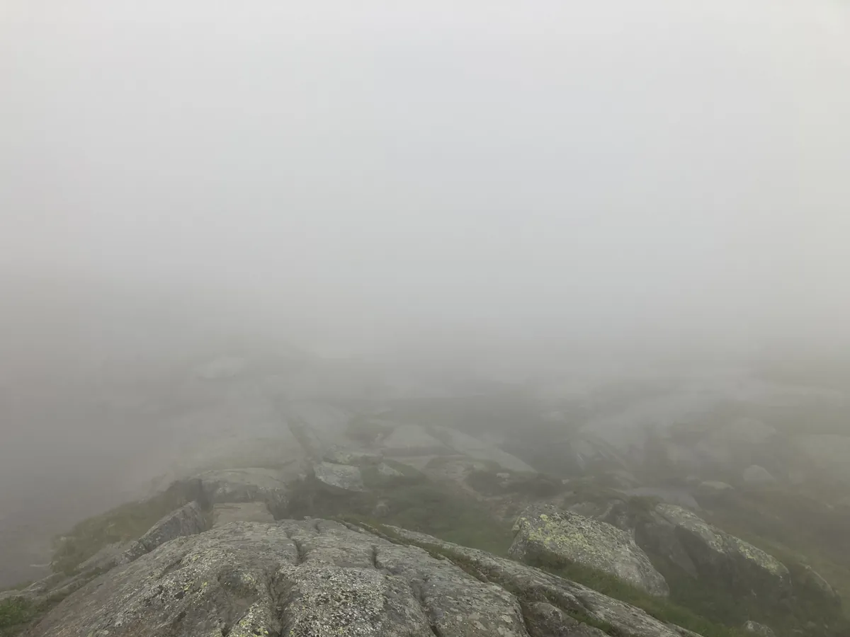 Ein felsiger Weg verschwindet im dichten Nebel