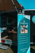 Informationsbanner von Seaside Camper neben einem individuell ausgestatteten Mini-Camper, der einen gemütlichen Wohnraum und modulare Möbel zeigt.