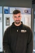 Mann mit Bart und kurzem Haar trägt einen schwarzen Pullover mit "MMSJ COMMUNICATION" Logo.