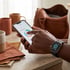 A person wears a smartwatch and uses a smartphone displaying a health app with macro targets and circular progress charts.