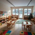 Heller Kita-Gruppenraum im Winter mit Kindertischen und Spielzeugregalen