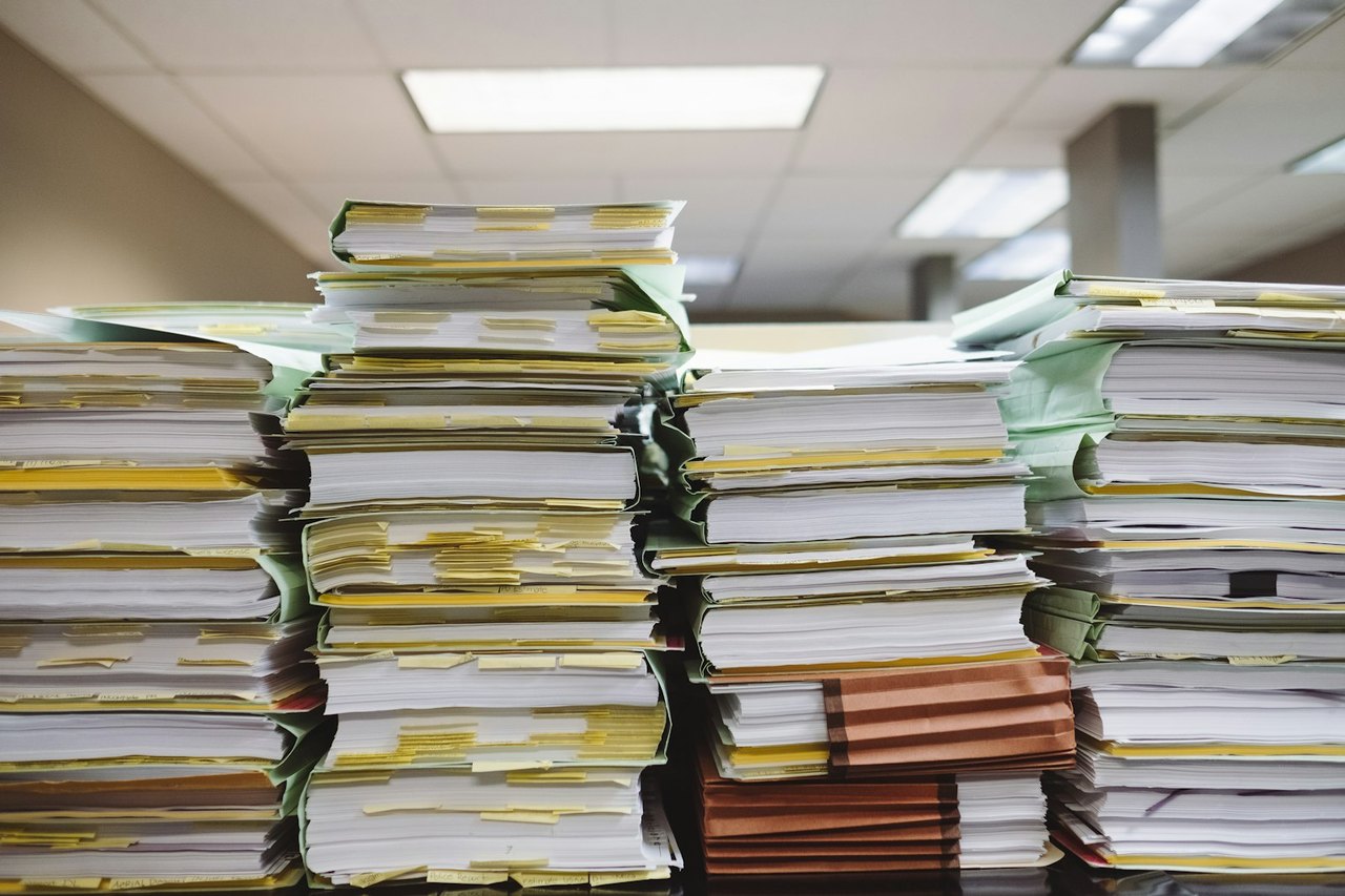 Hohe Stapel aus Akten und Papier auf einem Bürotisch