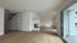 Geräumiges, leeres Wohnzimmer mit Holzboden, weißem Kamin, Treppe hinter Glas und großer Schiebetür.