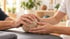 Hände eines Therapeuten führen die Hand eines Patienten bei einer Greifübung mit einem strukturierten Therapieball.