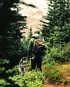 Hiker with a backpack and a husky dog on a trail through the Kasar Devi range, with Himalayas in the background