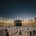 Luftaufnahme von Mekka bei Sonnenuntergang mit der beleuchteten al-Haram-Moschee und dem markanten Abraj Al Bait Uhrturm.