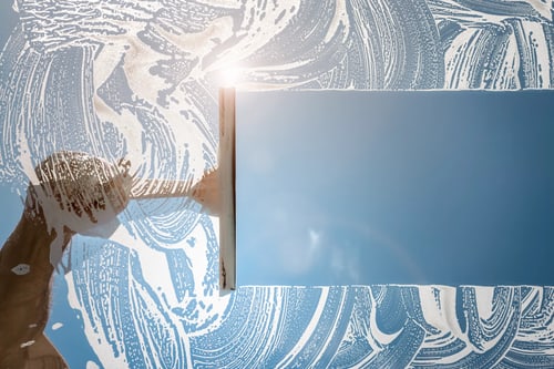 Fensterputzer zieht ein Fenster bei Sonnenschein ab