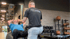 Ein Personal Trainer hilft einem älteren Mann bei Sit-ups auf einem Gymnastikball.