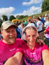 Selfie von zwei Menschen in pinken Diakonie-Laufshirts vor einer Läufergruppe.