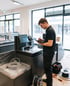Techniker in schwarzer Arbeitskleidung bedient ein Tablet bei der Installation einer Self-Checkout-Kasse im Einzelhandel.