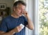 Mann mit juckenden Augen und Taschentuch am Fenster