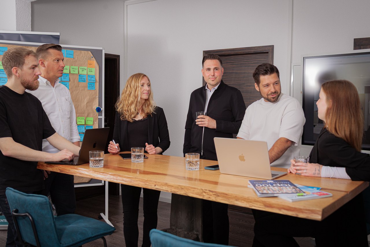 Das Team von Tobias Wolfrum Consulting im Gespräch an einem Holztisch