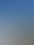 Ein Arbeiter montiert ein Edelstahlgeländer auf einer runden Beton-Aussichtsplattform vor blauem Himmel.