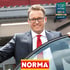 Lächelnder Mann im Anzug mit Brille lehnt sich aus einem Auto und hält eine "TOP ARBEITGEBER 2024" Auszeichnung.