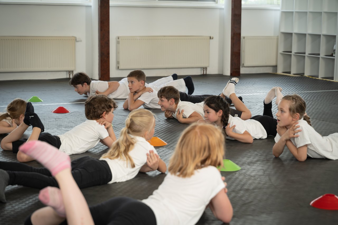 Kleine Kinder liegen bei einem Bewegungsspiel auf der Trainingsmatte