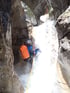 Person beim Canyoning an einem Wasserfall in einer Felsenschlucht.