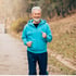 
A smiling elderly man jogs outdoors.