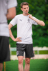 Ein Mann in einem weißen T-Shirt und schwarzen Shorts steht auf einem Rasenfeld.