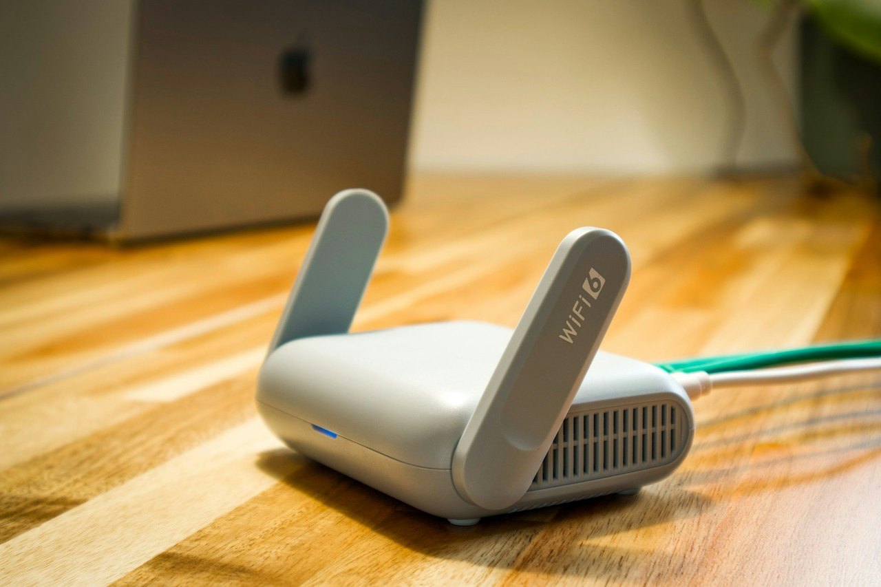 WLAN-Router mit zwei Antennen auf einem Holztisch, ein Netzwerkkabel ist angeschlossen
