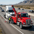 Towing Sandy heavy-duty towing service connecting a semi-truck to a heavy wrecker for roadside recovery on a busy highway.