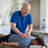 A chiropractor adjusts a male patient's upper back and shoulders