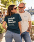 Frau im petrolfarbenen Wearmorrow® Shirt mit der Rückenbotschaft Vielfalt steht uns gut, neben ihr ein Mann im cremefarbenen Shirt