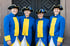 Vier lächelnde Frauen in blau-gelben historischen Uniformen mit Dreispitz-Hüten stehen vor einer dunklen Holztür.