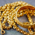 Goldene Kette und Ring auf grauem Hintergrund.