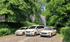 Drei Taxis – ein VW, ein Mercedes-Benz Van und ein Mercedes-Benz Kombi – stehen auf einem gepflasterten Weg.