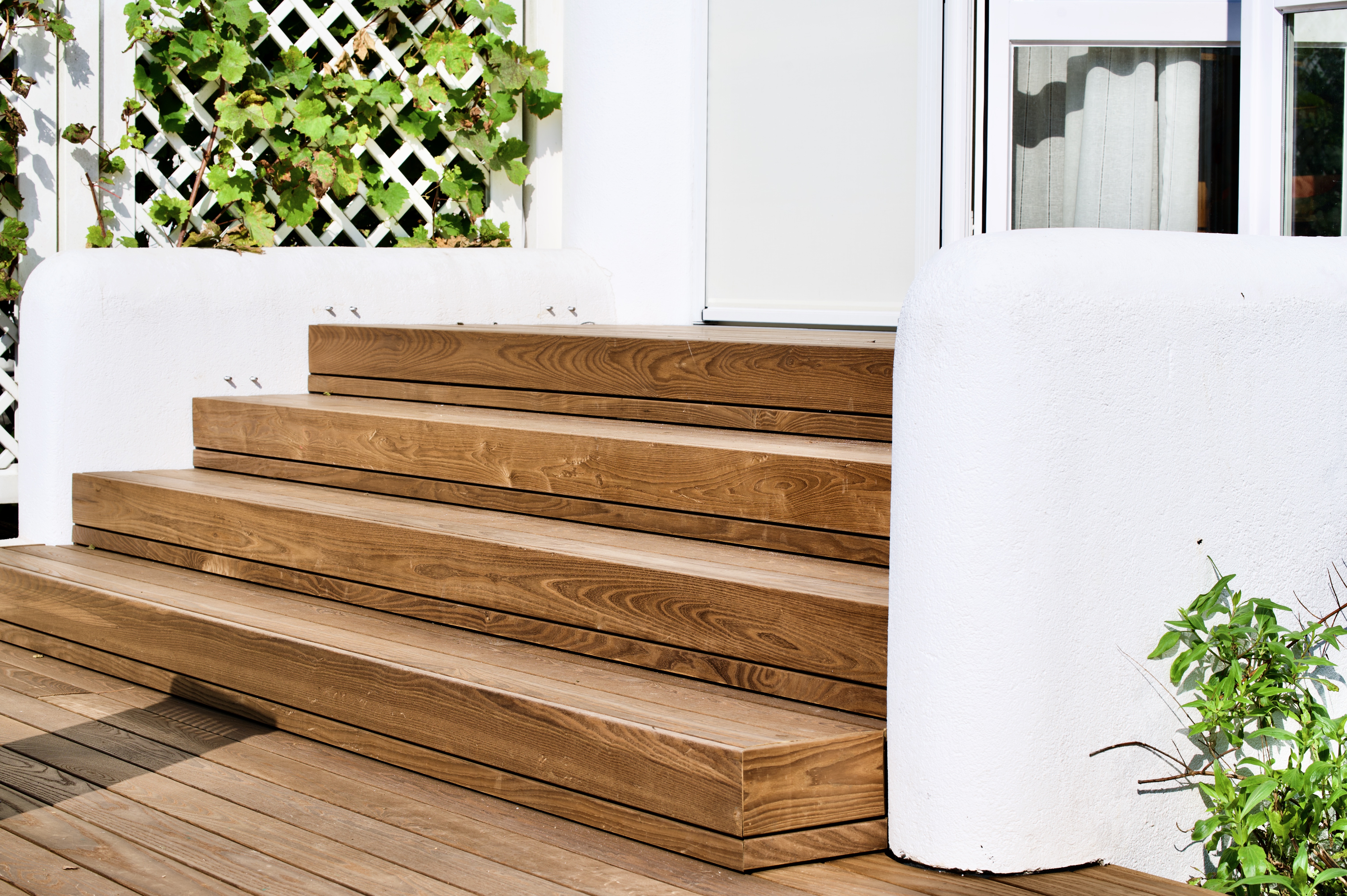 Holzterrasse aus Thermoesche mit breiten Holzstufen am Wohnhaus