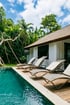 Luxury resort with a swimming pool, wooden deck, five lounge chairs, and lush tropical foliage under a blue sky.