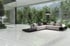 Großzügiges Wohnzimmer mit Glasfront zum Garten, Ecksofa und hellem Marmorboden