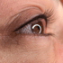 Nahaufnahme eines braunen Auges mit langen Wimpern und sichtbaren Hautdetails um das Auge herum.