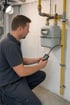 Monteur führt an der Gasleitung neben dem Gaszähler eine Druckprüfung mit digitalem Messgerät durch