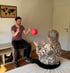 Ein Mann und eine Frau spielen mit einem rosa Ball in einem hellen Raum.