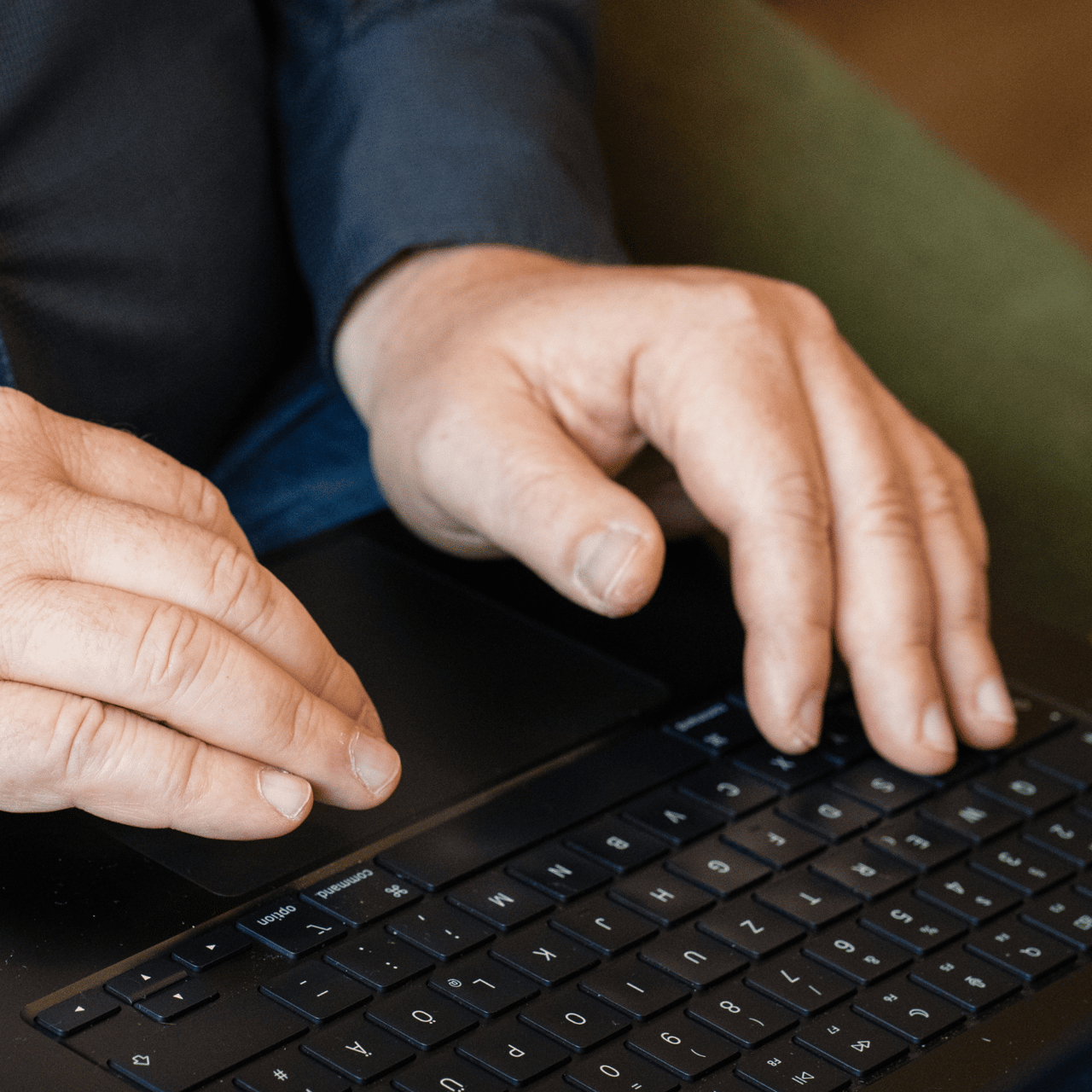 Nahaufnahme von Händen, die auf einer Laptop-Tastatur tippen.
