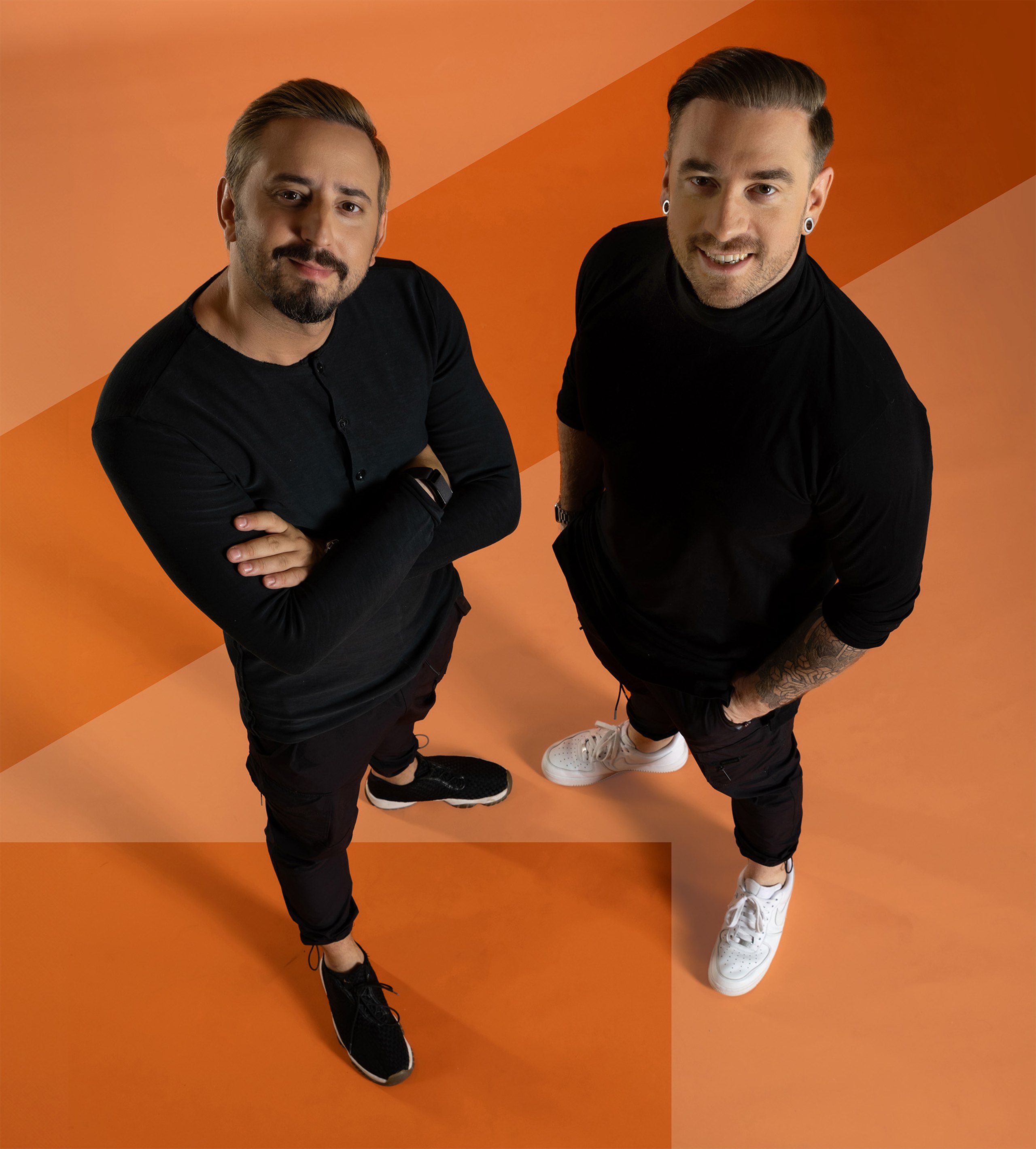 Die GYMPOD Gründer Aleksander Ostojic und Tim Horst vor orangem Hintergrund